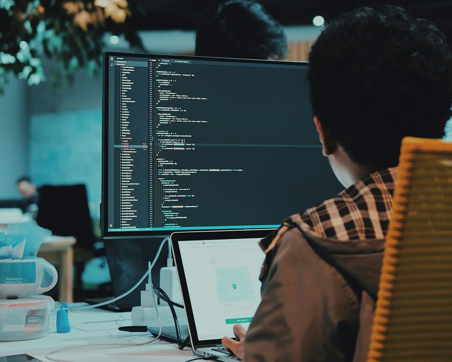Du code affiché à l'écran, un développeur de dos